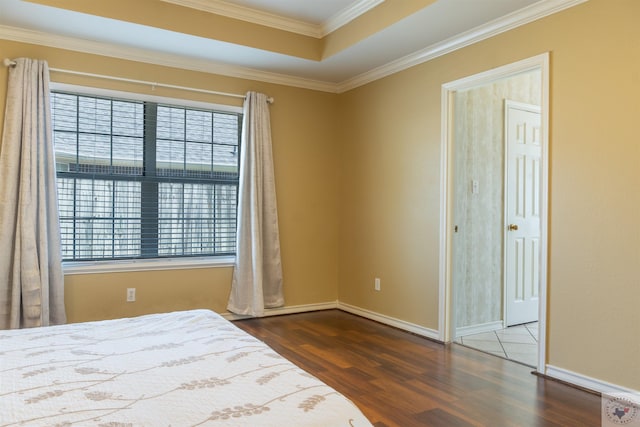 bedroom featuring dark hardwood / wood-style flooring, a tray ceiling, and ornamental molding