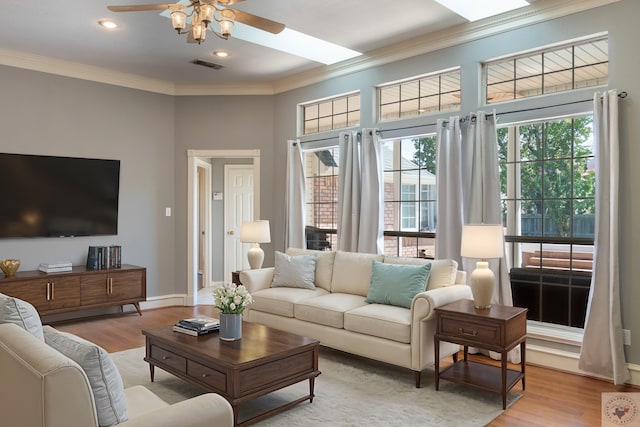 living room with hardwood / wood-style flooring, a wealth of natural light, a skylight, and ceiling fan