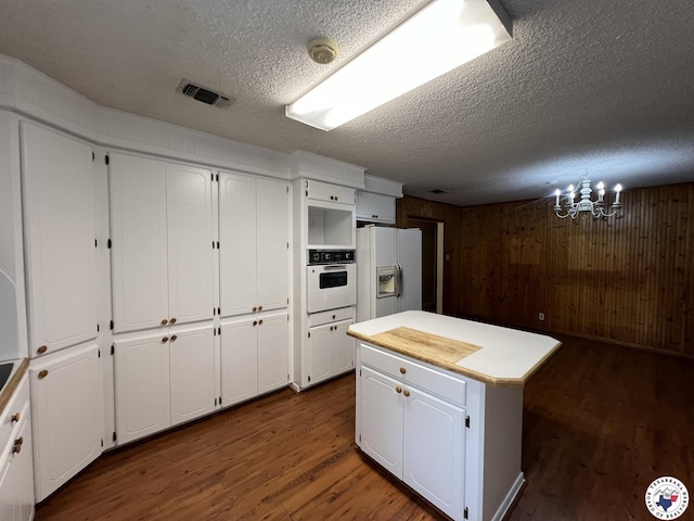 6 Arnold Dr, Texarkana, AR 71854 - kitchen with white appliances, a textured ceiling, white cabinets, dark wood-style floors, and a chandelier