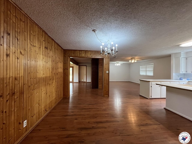 6 Arnold Dr, Texarkana, AR 71854 - unfurnished dining area featuring wood walls, dark wood-style flooring, a textured ceiling, a chandelier, and ceiling fan