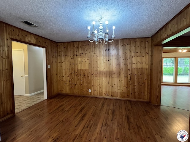 6 Arnold Dr, Texarkana, AR 71854 - spare room with a chandelier, a textured ceiling, wooden walls, wood finished floors, and baseboards