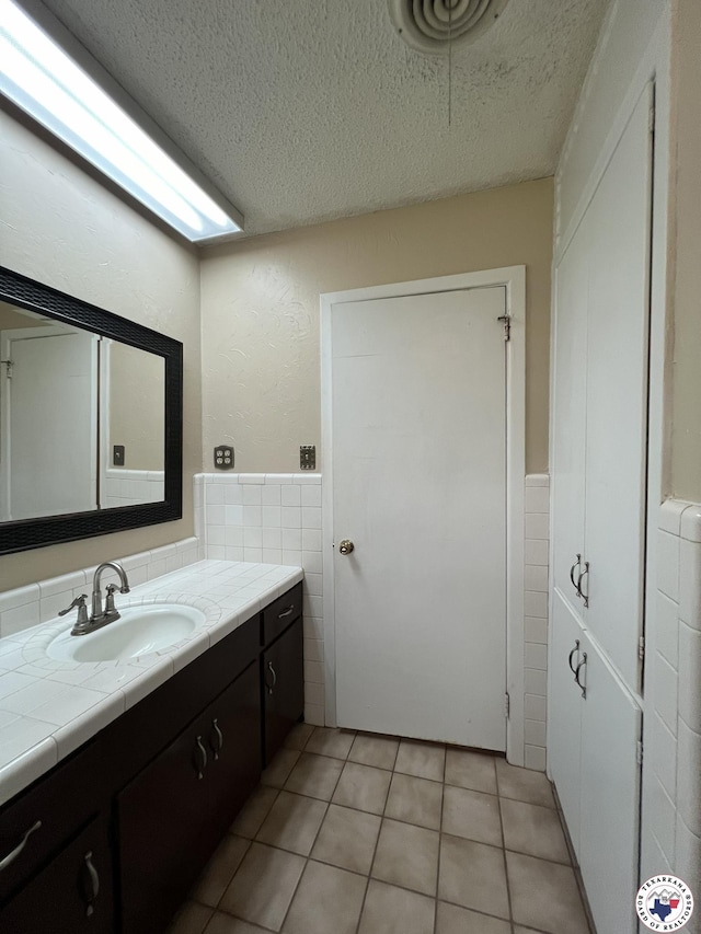 6 Arnold Dr, Texarkana, AR 71854 - bathroom with tile walls, a textured ceiling, wainscoting, vanity, and tile patterned flooring