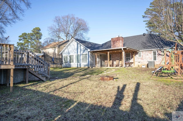 rear view of property with a playground, cooling unit, a lawn, and a trampoline