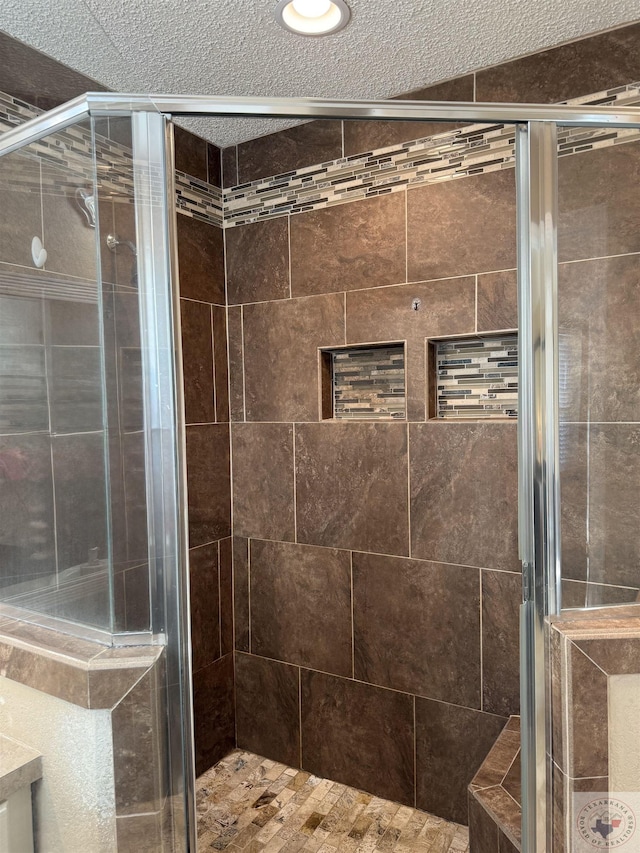 bathroom featuring a textured ceiling, an enclosed shower, and vanity