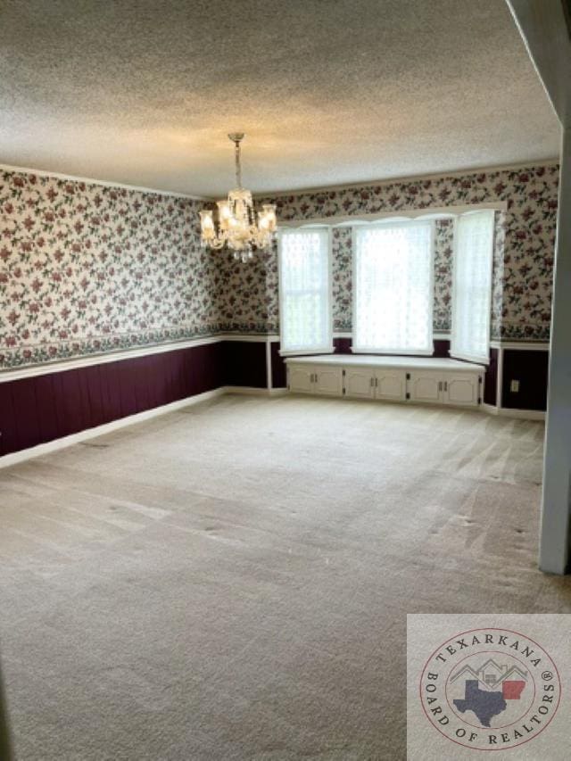 spare room with carpet and an inviting chandelier