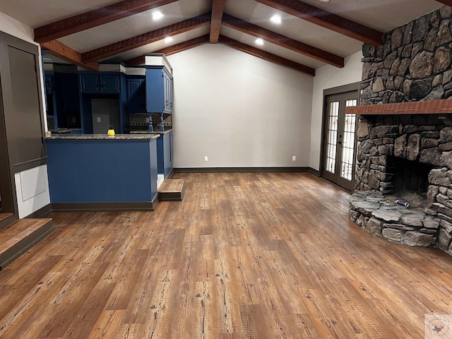 unfurnished living room featuring vaulted ceiling with beams, a stone fireplace, and dark hardwood / wood-style flooring