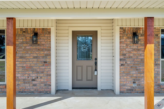 doorway to property with covered porch and brick siding