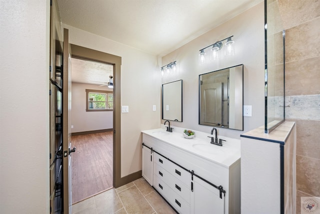 full bathroom featuring double vanity, tile patterned flooring, baseboards, and a sink