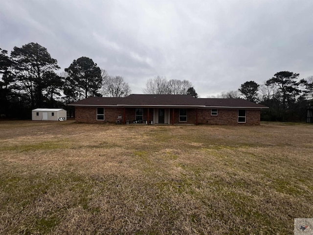 view of front of house with brick siding, an outdoor structure, and a front lawn