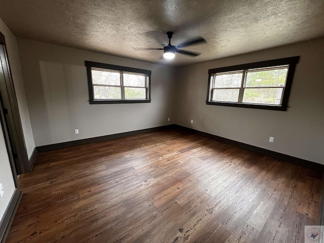 unfurnished room with a healthy amount of sunlight, a textured ceiling, and dark wood-type flooring