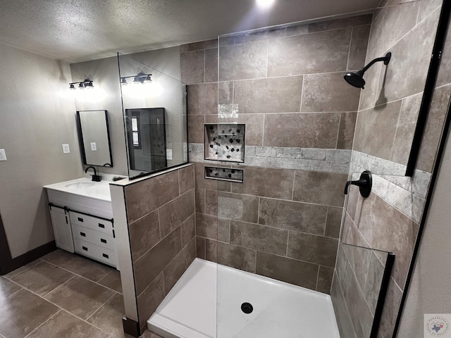 bathroom featuring a tile shower, a textured ceiling, and vanity