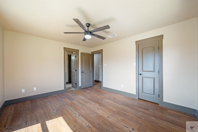 unfurnished bedroom with hardwood / wood-style flooring, baseboards, visible vents, and a ceiling fan