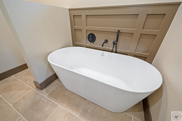 bathroom with tile patterned flooring, a freestanding tub, and baseboards