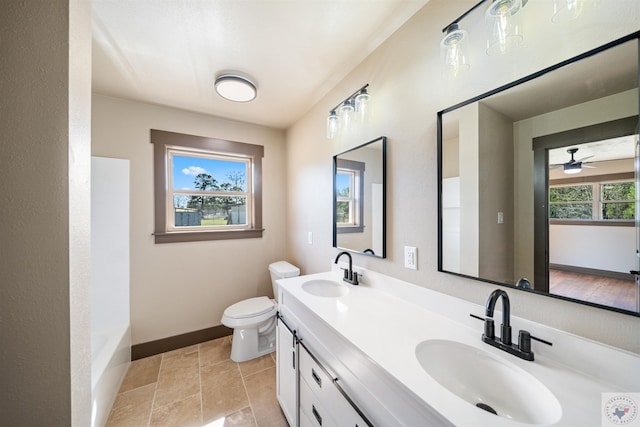 bathroom featuring toilet, double vanity, baseboards, and a sink