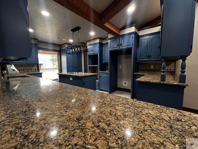 kitchen featuring sink, blue cabinetry, beamed ceiling, and dark stone counters