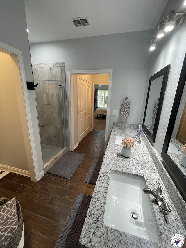 ensuite bathroom featuring ensuite bath, wood finish floors, a sink, and visible vents