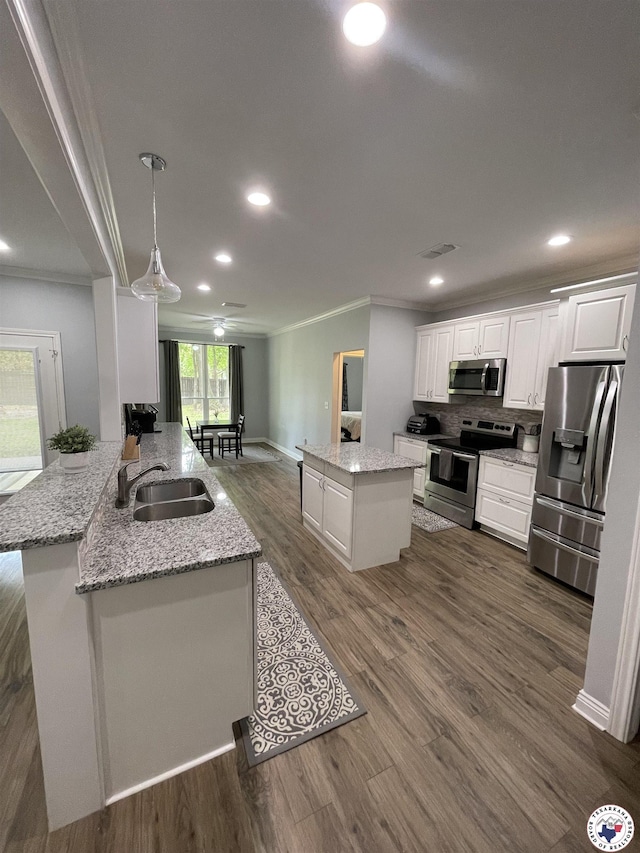 kitchen featuring a sink, ornamental molding, stainless steel appliances, white cabinetry, and a kitchen island