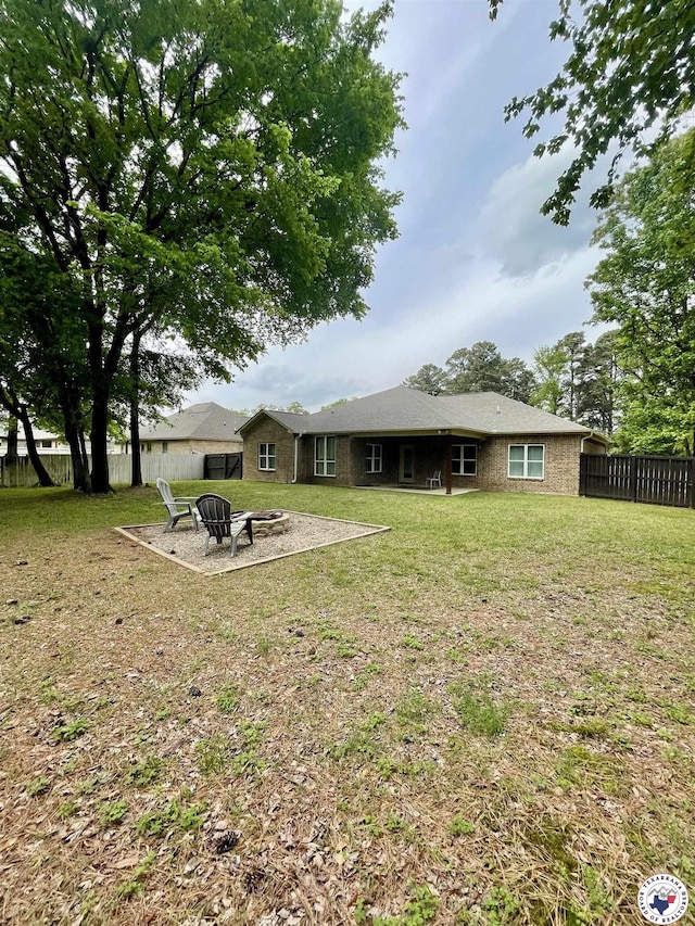 rear view of house featuring a fire pit, fence private yard, and a lawn