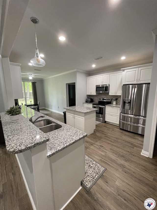 kitchen with stainless steel appliances, visible vents, crown molding, a peninsula, and white cabinetry