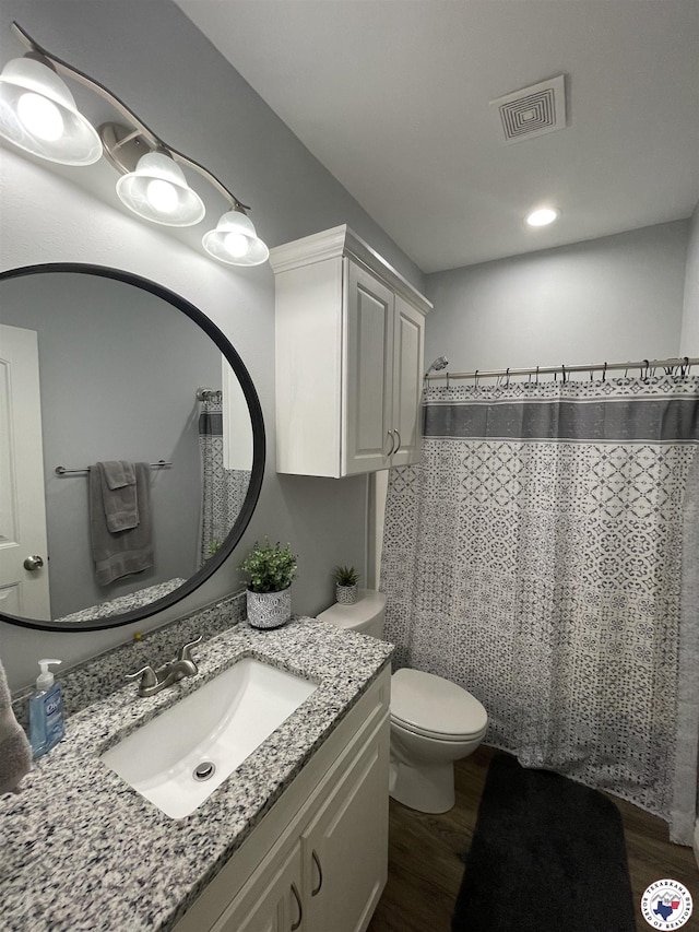 bathroom with toilet, visible vents, wood finished floors, a shower with shower curtain, and vanity