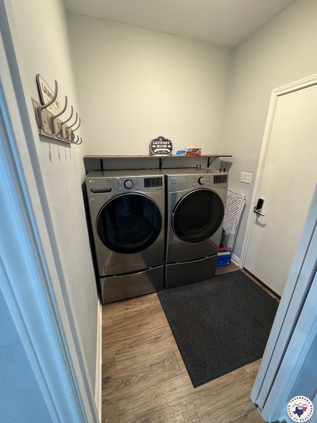 laundry room with separate washer and dryer, baseboards, wood finished floors, and laundry area