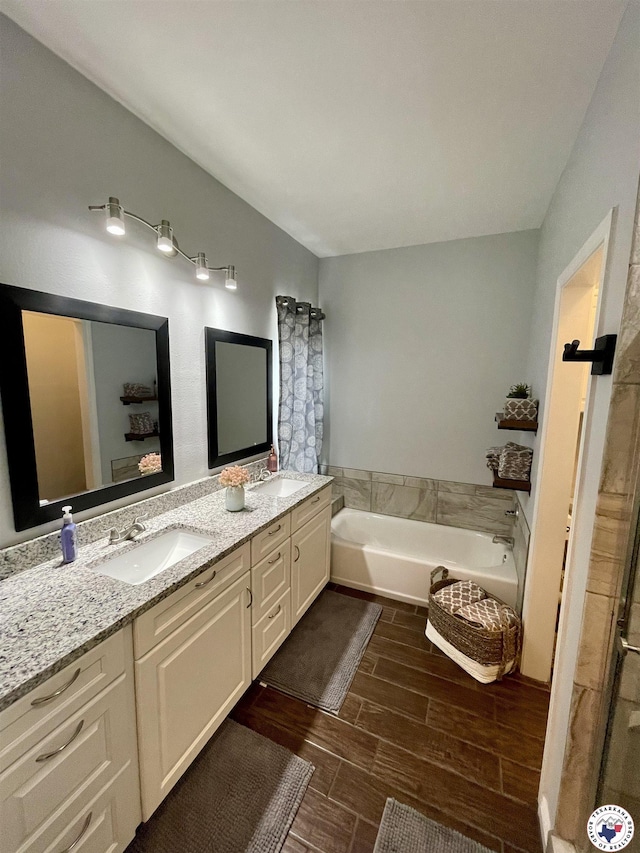 bathroom with a garden tub, wood finished floors, a sink, and double vanity