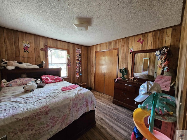 bedroom featuring hardwood / wood-style flooring, a textured ceiling, a closet, and wooden walls