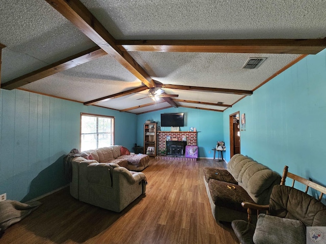 living room with wood-type flooring, ceiling fan, a fireplace, a textured ceiling, and vaulted ceiling with beams