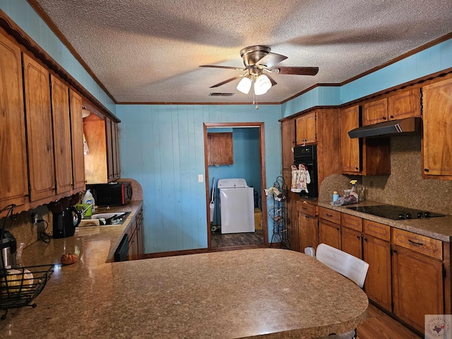 kitchen with black appliances, kitchen peninsula, washer / dryer, and crown molding