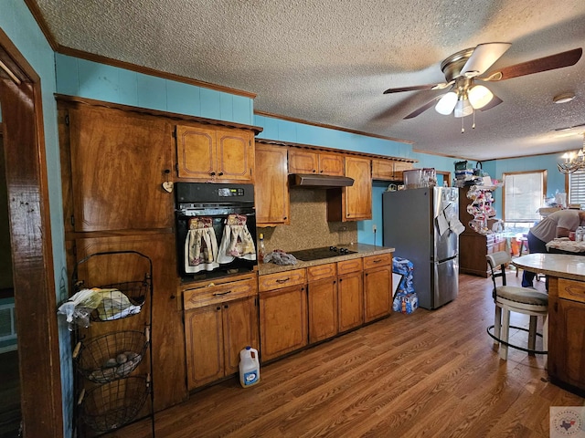 kitchen with black appliances, crown molding, hardwood / wood-style flooring, decorative backsplash, and ceiling fan with notable chandelier