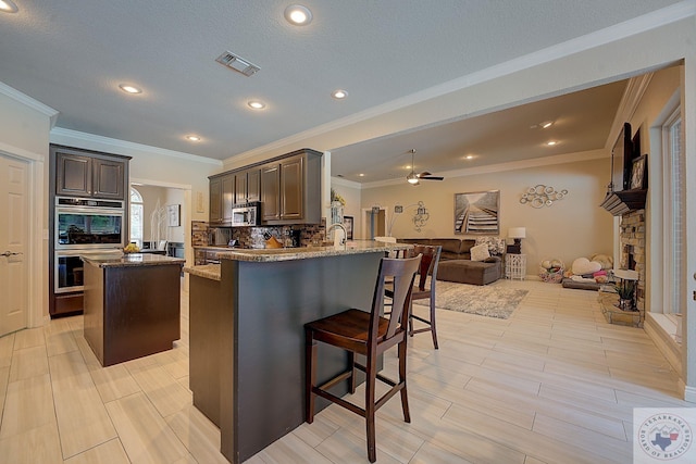 kitchen featuring appliances with stainless steel finishes, a center island, tasteful backsplash, a kitchen breakfast bar, and kitchen peninsula