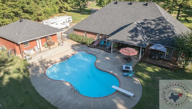 view of pool featuring a patio area, a lawn, and a diving board