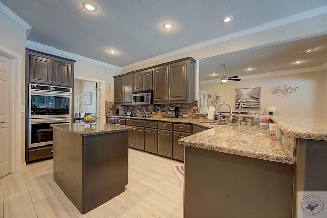 kitchen featuring appliances with stainless steel finishes, a center island, decorative backsplash, sink, and kitchen peninsula