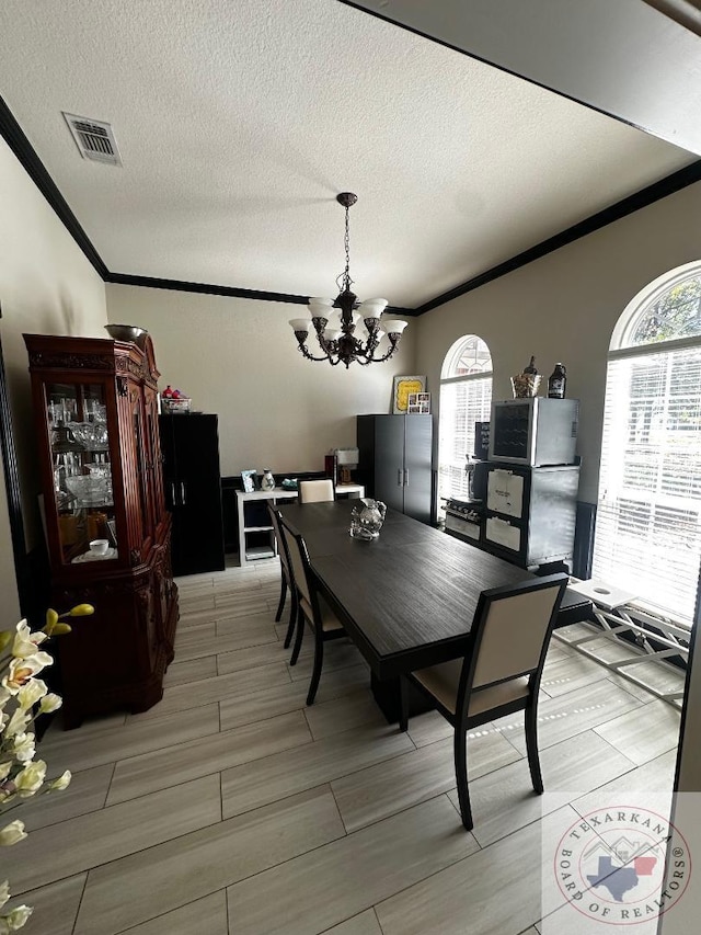 dining area featuring a textured ceiling, a chandelier, and ornamental molding