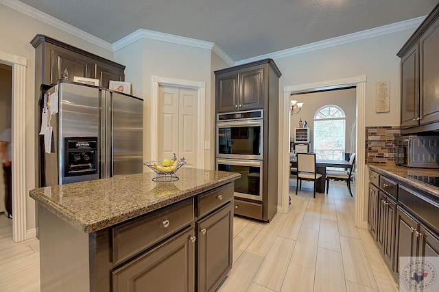 kitchen featuring appliances with stainless steel finishes, backsplash, light stone counters, a center island, and dark brown cabinetry