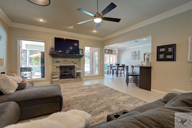 living room with light hardwood / wood-style floors, ornamental molding, ceiling fan, and a fireplace