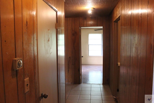 hall with wood walls and light tile patterned flooring