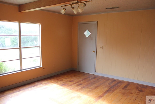 foyer entrance with plenty of natural light, light hardwood / wood-style flooring, wood walls, and beamed ceiling