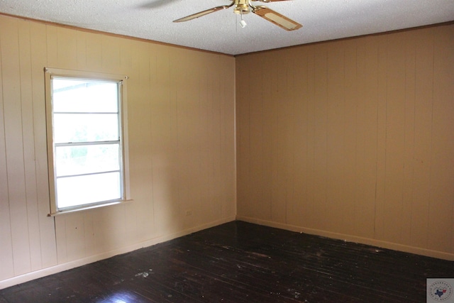 unfurnished room featuring ceiling fan, a textured ceiling, dark hardwood / wood-style flooring, and wooden walls