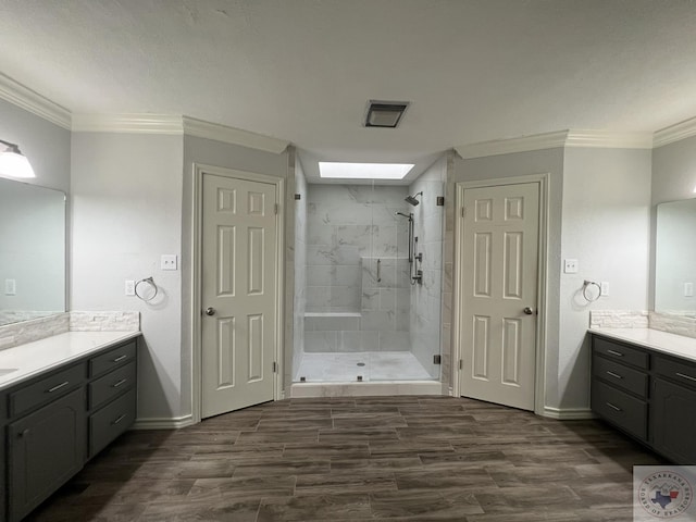 bathroom with vanity, a skylight, crown molding, and hardwood / wood-style flooring