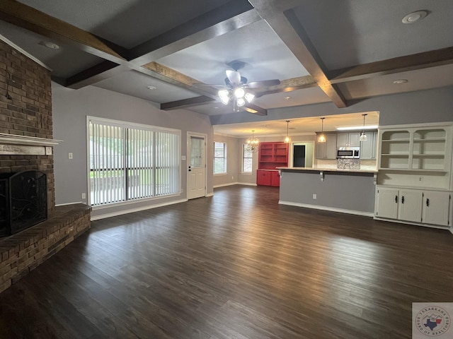 unfurnished living room with beamed ceiling, coffered ceiling, a brick fireplace, dark hardwood / wood-style flooring, and ceiling fan with notable chandelier