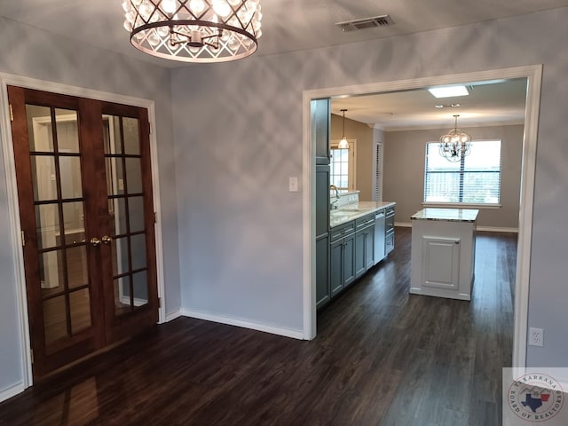 kitchen featuring dark hardwood / wood-style flooring, french doors, an inviting chandelier, hanging light fixtures, and light stone counters