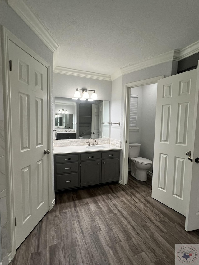 bathroom featuring crown molding, hardwood / wood-style floors, toilet, and vanity