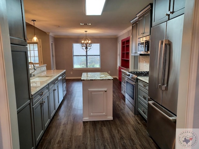 kitchen with hanging light fixtures, appliances with stainless steel finishes, sink, light stone counters, and a kitchen island