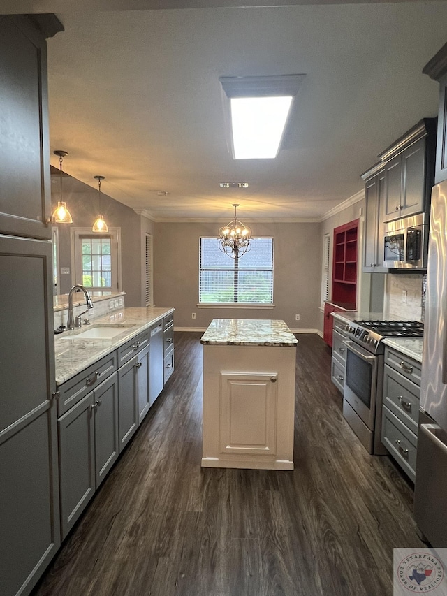 kitchen with a center island, light stone countertops, appliances with stainless steel finishes, gray cabinetry, and decorative light fixtures