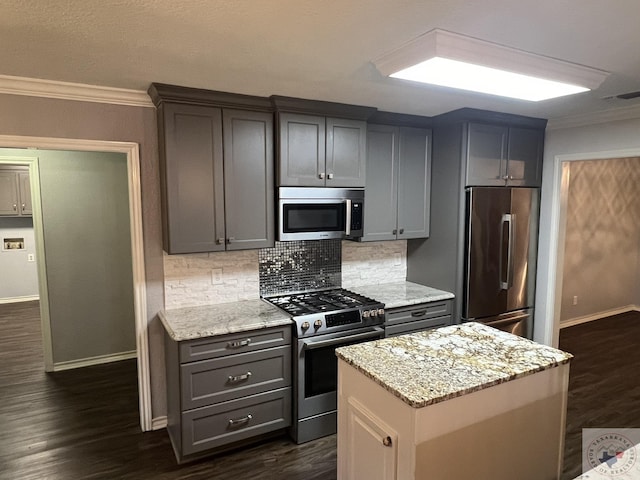 kitchen featuring stainless steel appliances, a center island, light stone counters, and crown molding