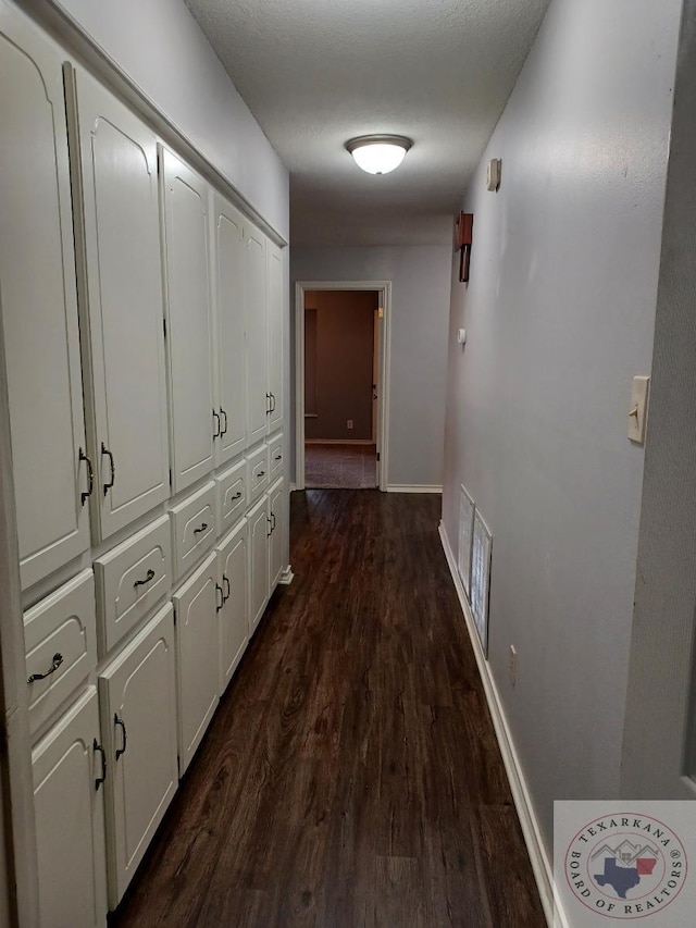 hall with a textured ceiling and dark hardwood / wood-style flooring