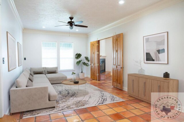 living room with a textured ceiling, light tile patterned floors, ceiling fan, and ornamental molding