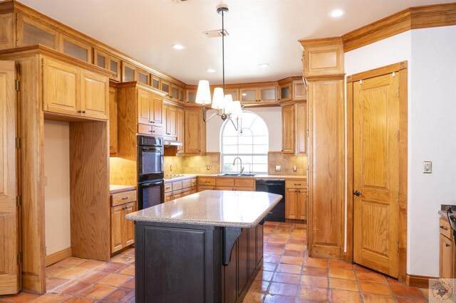 kitchen with light stone countertops, black appliances, a kitchen island, sink, and backsplash