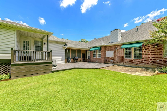 rear view of property featuring a deck, a yard, and a patio area